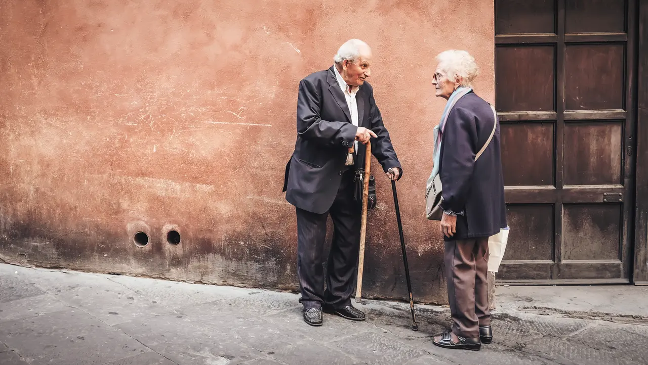 Hai người cao niên trò chuyện ngoài trời tại Siena, Italy